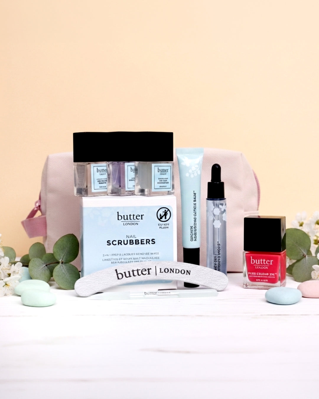 Butter London nail care set with polishes scrubbers a curved file and a pale pink bag in the background.