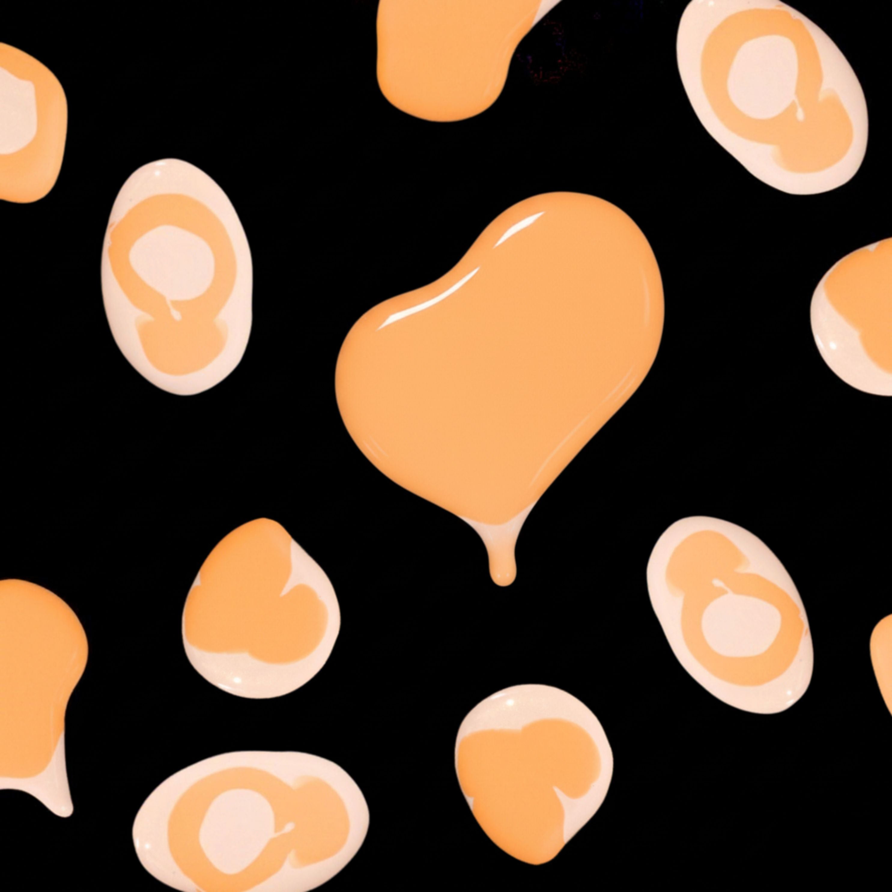 Orange nail polish droplets scattered on a black background for a Halloween themed image