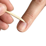 Close up of a wooden cuticle pusher held near a fingernail, used to push back cuticles