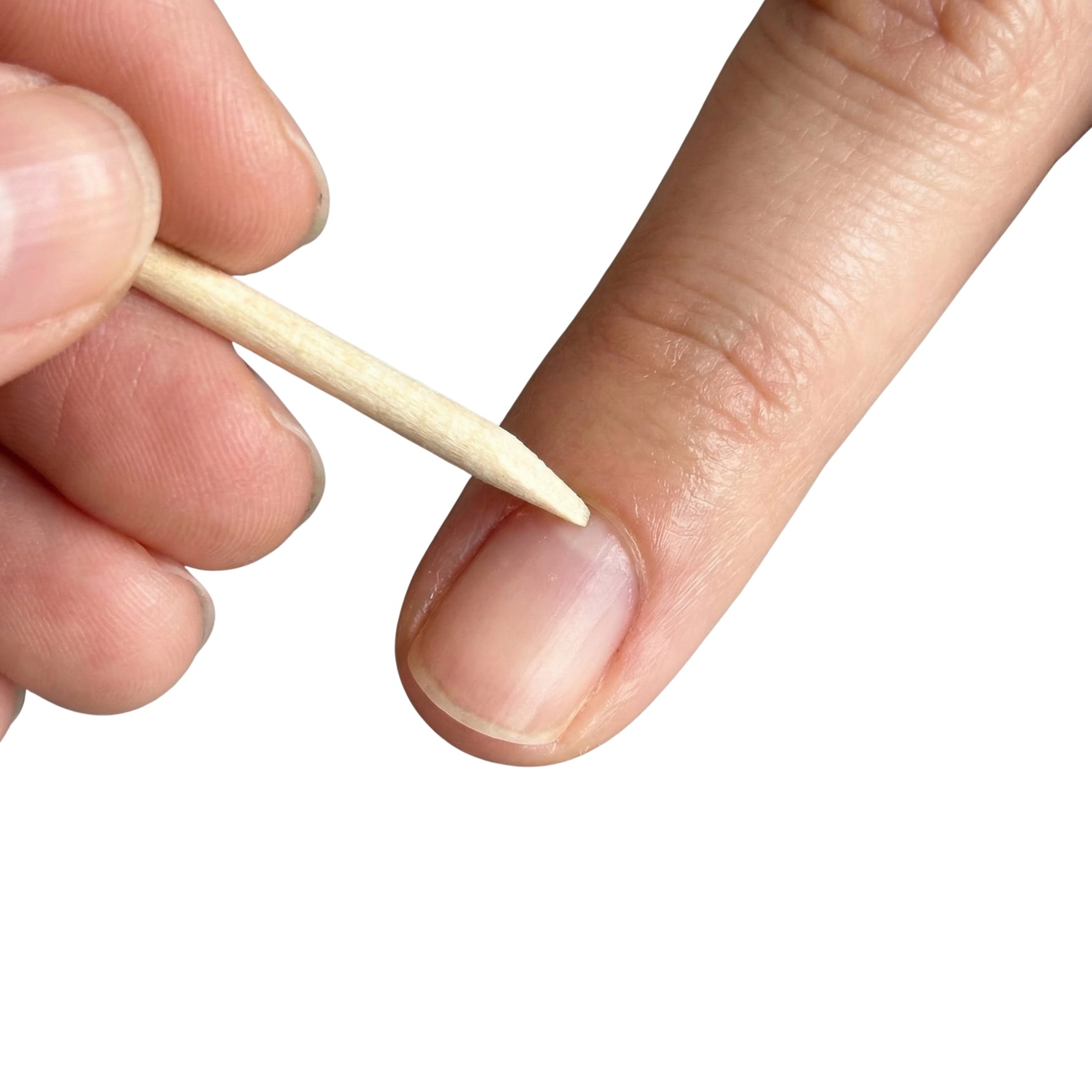 Close up of a wooden cuticle pusher held near a fingernail, used to push back cuticles
