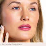 Close-up of a woman with glossy pink lips wearing Raspberry Spritz lip color.