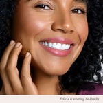 Close-up of a smiling woman with glossy peach lips wearing Silky Pout Creamy Lip Chubby in So Peachy.
