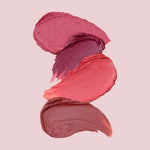Three lip color swatches in pink, mauve and rose tones on a pale pink background